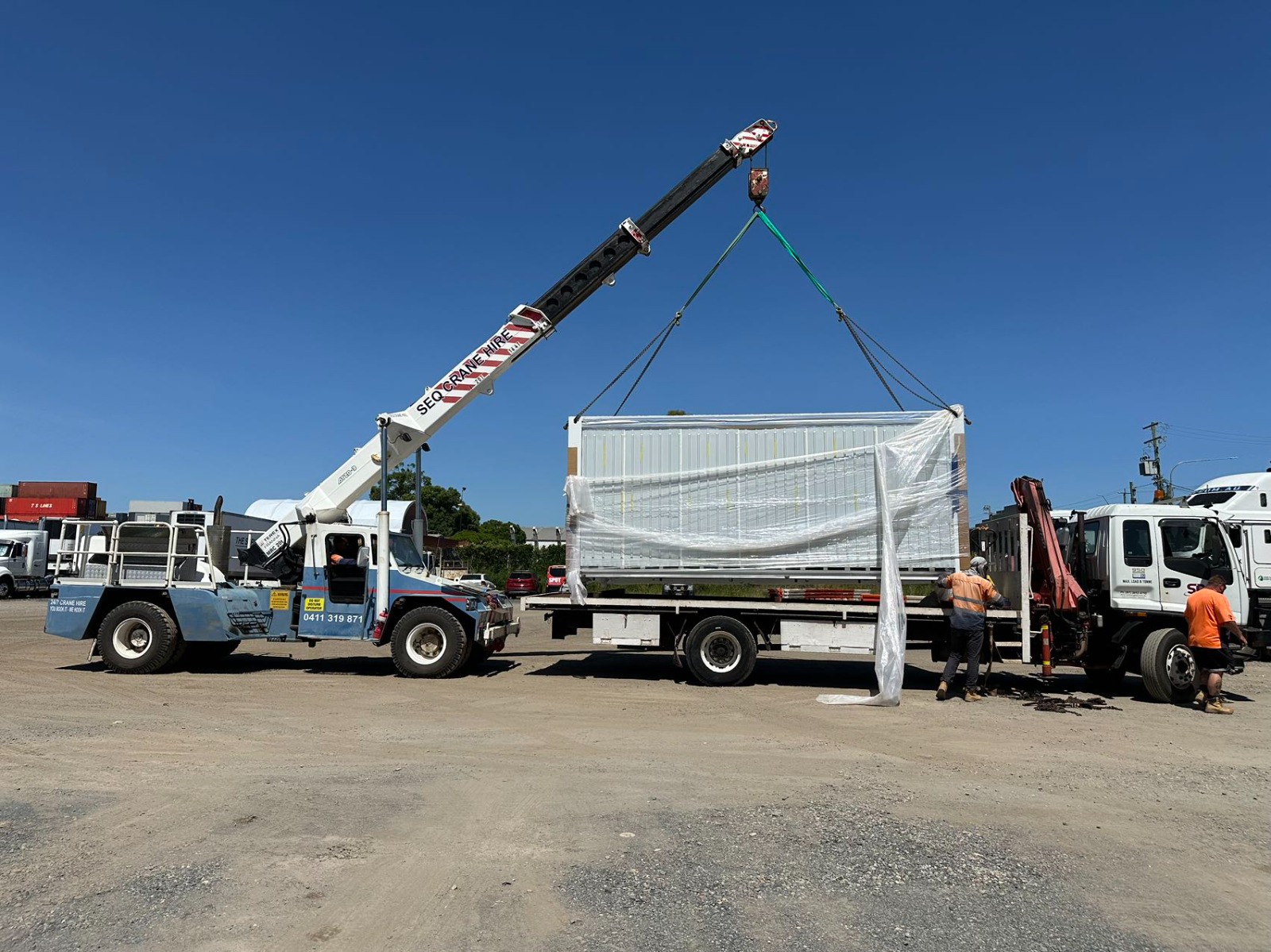 Eco Nest House module secured on a flatbed truck being lifted by mobile crane